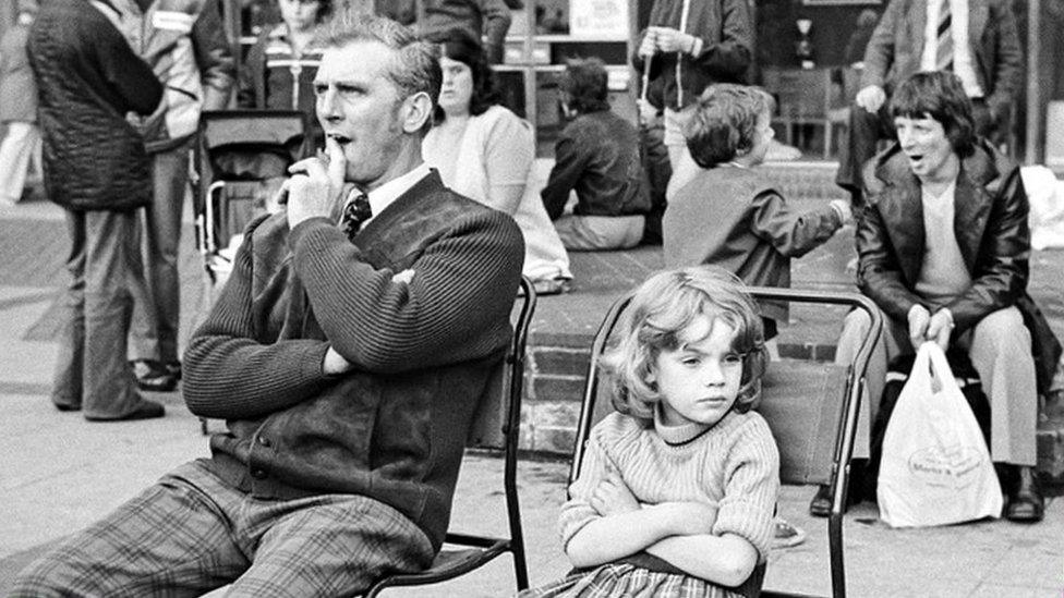 Man and young girl sitting on chairs at the market