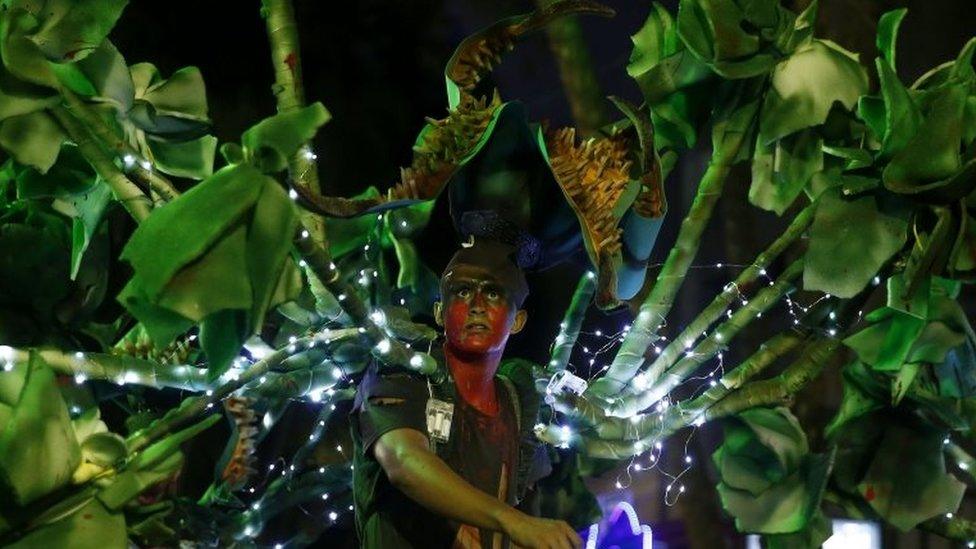 A man disguised as a man-eating tree walks among people at the parade in Medellín