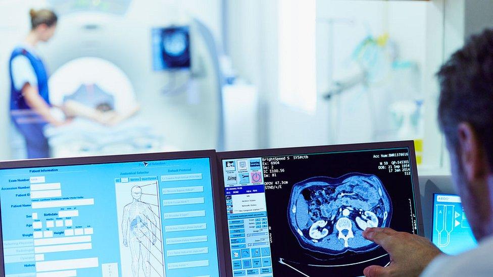 doctor looking at CT scan with person in scanner in the background