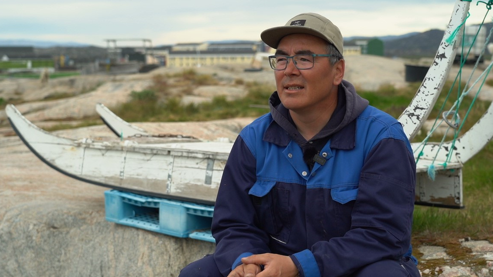 Kaleeraq Mathaeussen sits in front of an old wooden dog sled