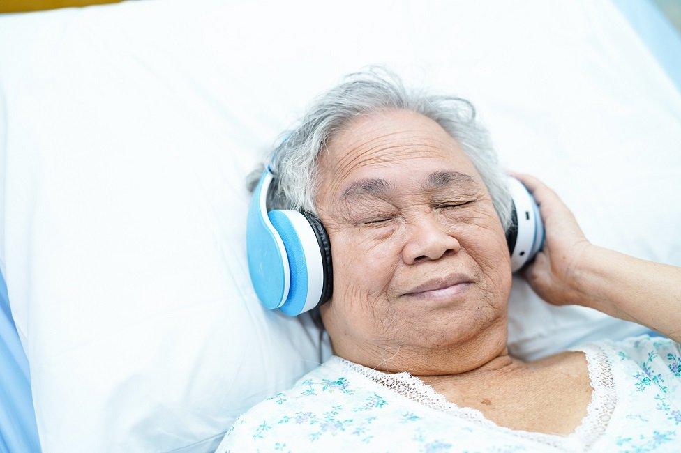 Woman in hospital bed wearing headphones