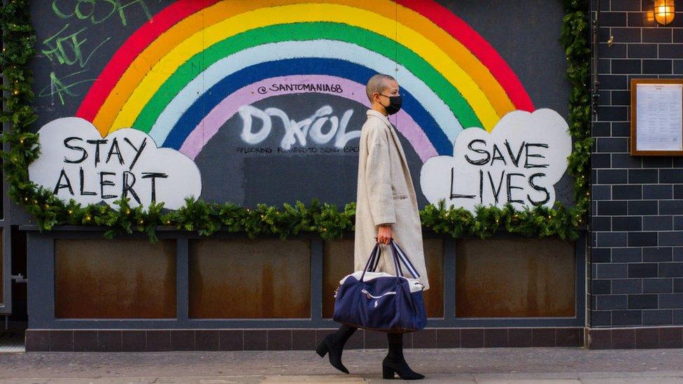 Woman walks past a "stay alert" sign