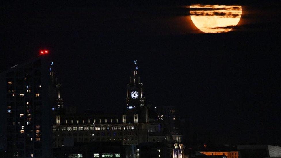 Buck moon rising through clouds behind the Liver Building in Liverpool