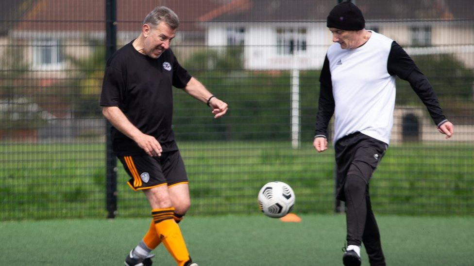 Two men play walking football on an all-weather pitch as part of the Bristol Walking Festival