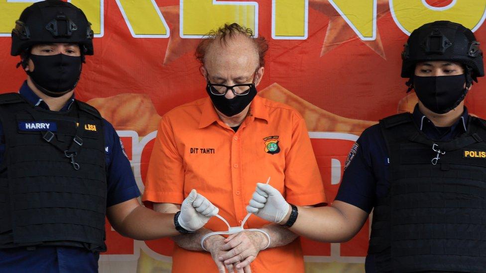 Police officers escort Francois Camille Abello of France (C) during a press conference at Jakarta's police headquarters in Jakarta, Indonesia, 09 July 2020