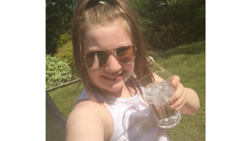 Girl poses for selfie with glass of water