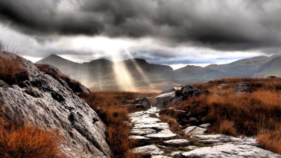 The sun creeping through dark clouds after a storm on the Rhyd Ddu path, Snowdon