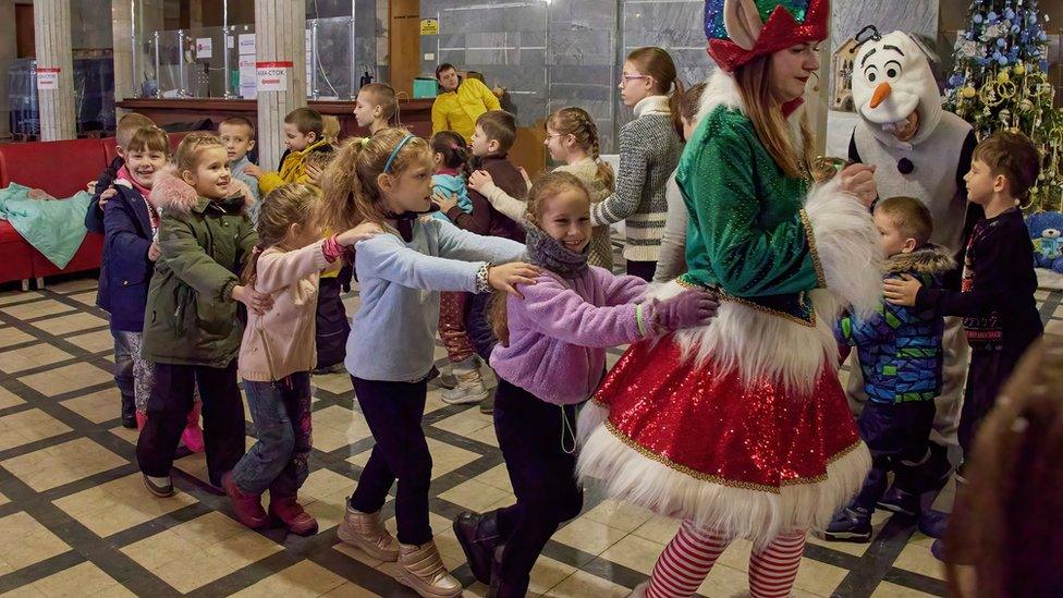 Ukrainian volunteers perform with local children during the celebration of St. Nicolas day according to the Orthodox calendar, in Kharkiv, Ukraine, 17 December 2022.