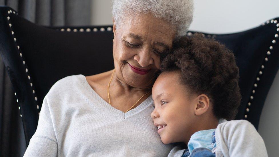 Grandparent hugs grandchild.