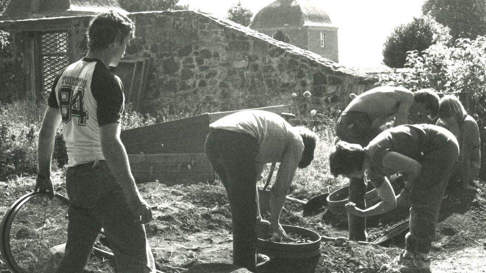 black and white image of people digging up field