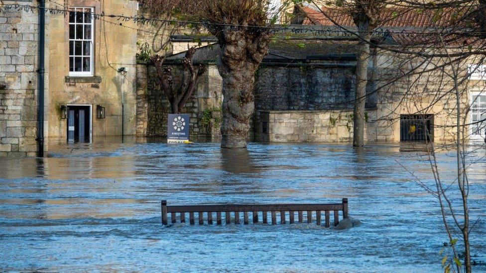 A bench is surrounded by flood water from the River Avon after it burst its banks and flooded nearby riverside properties on November 25, 2024 in Bradford on Avon.