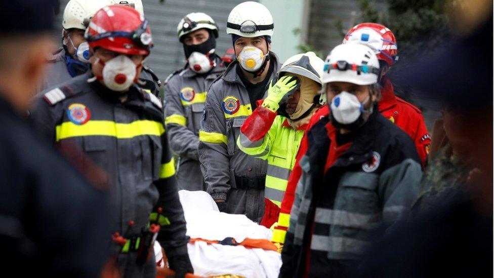 Emergency personnel carry a body on a stretcher as they work in a collapsed building in Durres