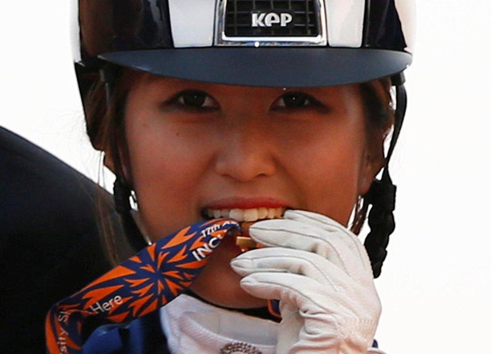 South Korea's Chung Yoo-ra , bites her gold medal as she poses after winning the equestrian Dressage Team competition at the Dream Park Equestrian Venue during the 17th Asian Games in Incheon, South Korea, on 20 September 2014.