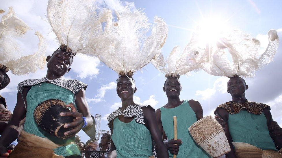 Performers, wearing traditional dress, greet Pope Francis upon his arrival at Kololo airstrip in Kampala