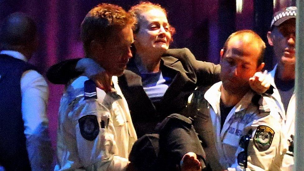 A freed hostage is carried from the Lindt cafe