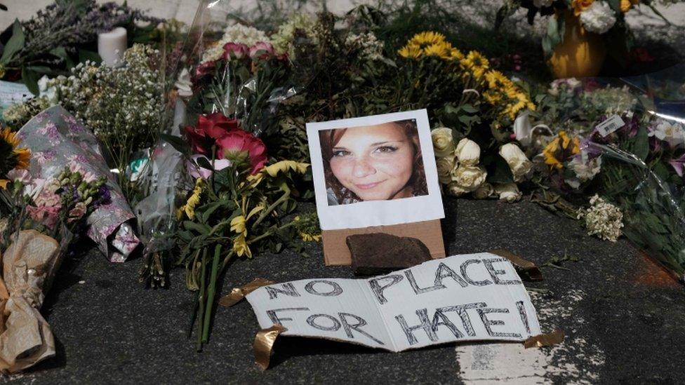 A memorial shows a picture of Heather Heyer at her place of death with 'no place for hate' sign by it.