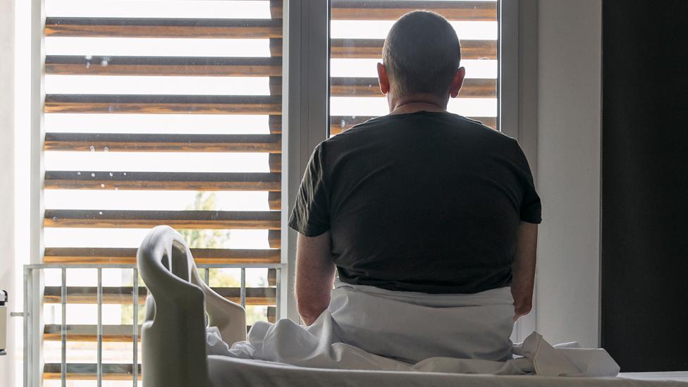 Stock image of an anonymous person sat on a bed