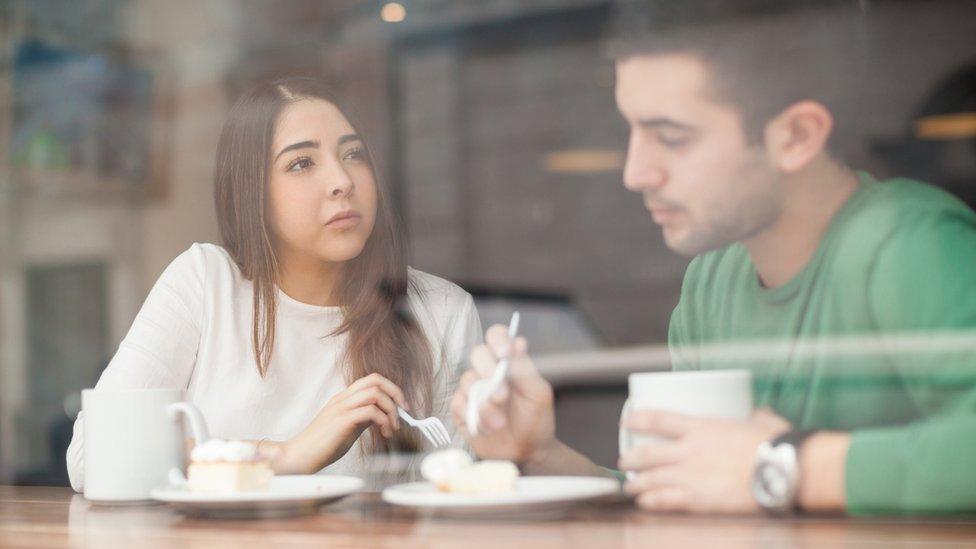 man and woman chatting over coffee and cake