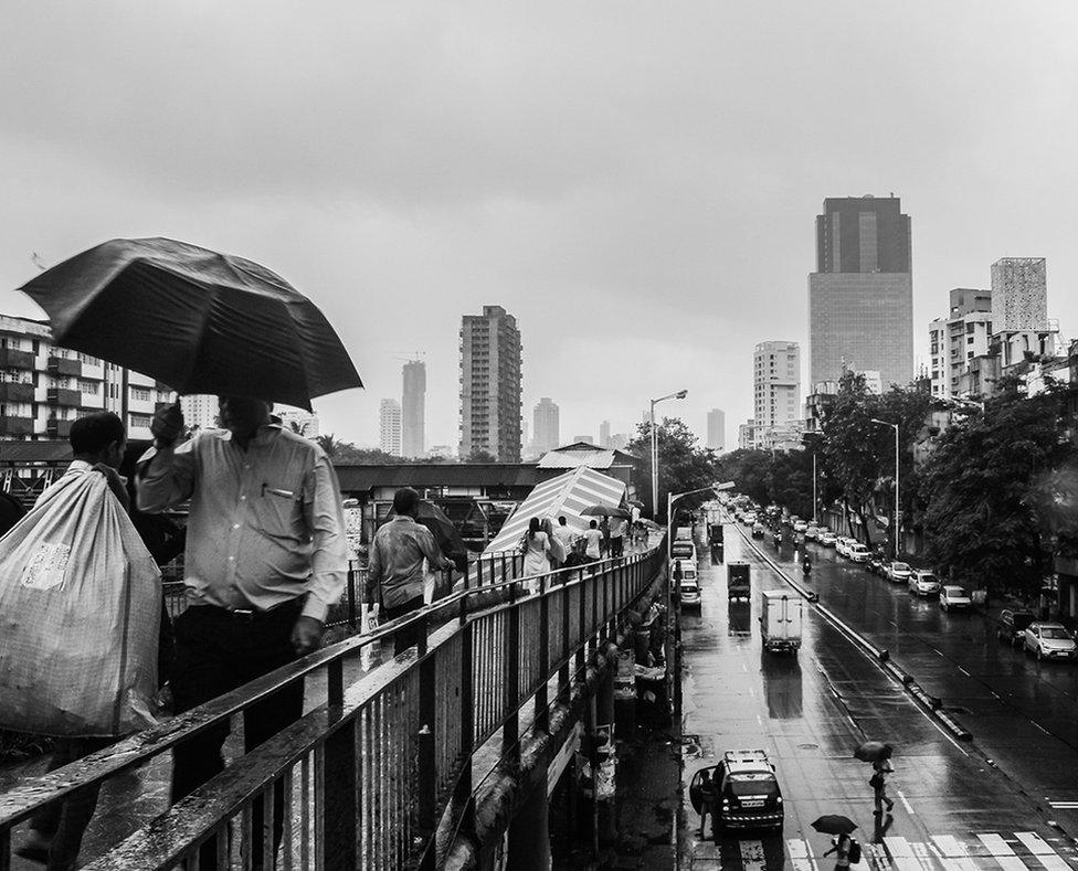 Rain pours on the city of Mumbai , people are getting wet as they use the over pass