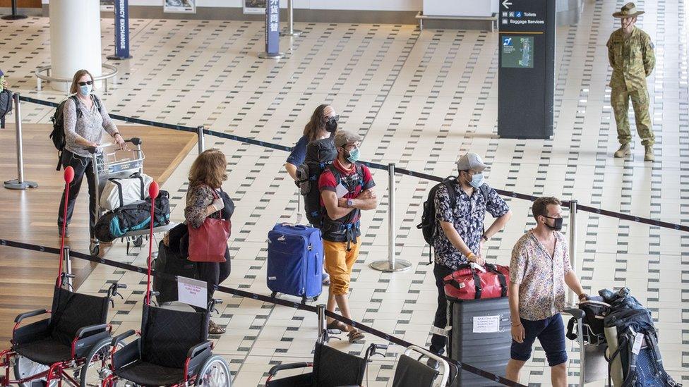 Australian passengers from an evacuation flight walk through an airport in Australia