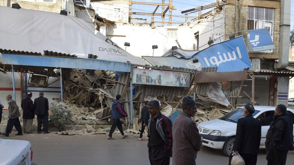 People look on around the damaged buildings after 6.4 magnitude earthquake that hit western Iran near the border with Iraq, in Tehran, Iran on 26 November 2018