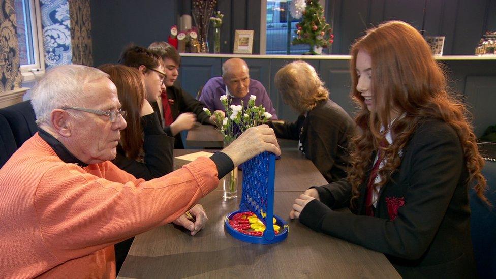 School pupil plays Connect 4 with a resident