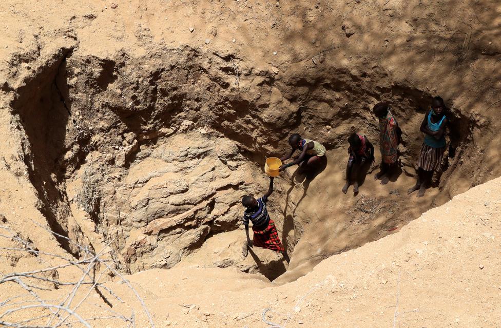 Members of the Turkana pastoralist community collect water from an open well dug on a dry riverbed in Kakimat village in Turkana, Kenya, 27 September 2022.