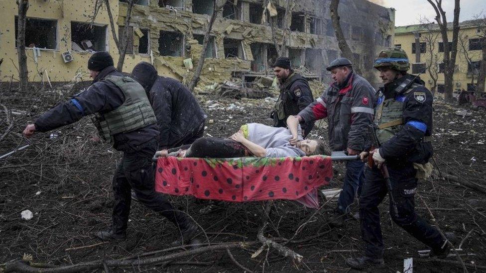 Ukrainian emergency employees and volunteers carry an injured pregnant woman from the damaged by shelling maternity hospital in Mariupol, Ukraine, Wednesday, March 9, 2022