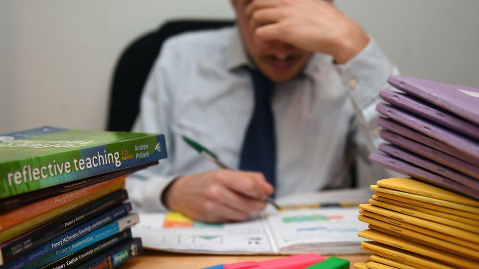 teacher at desk with books