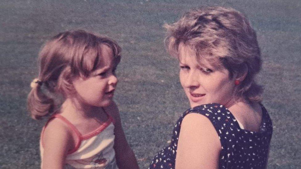 Young Samantha Brown sitting on the grass with her mother