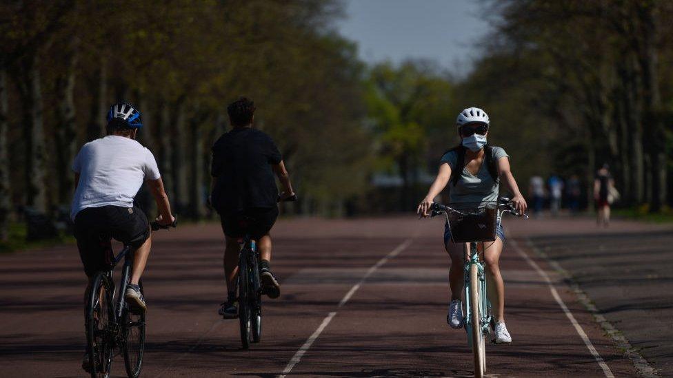 A cyclist wearing a mask is seen in Greenwich Park