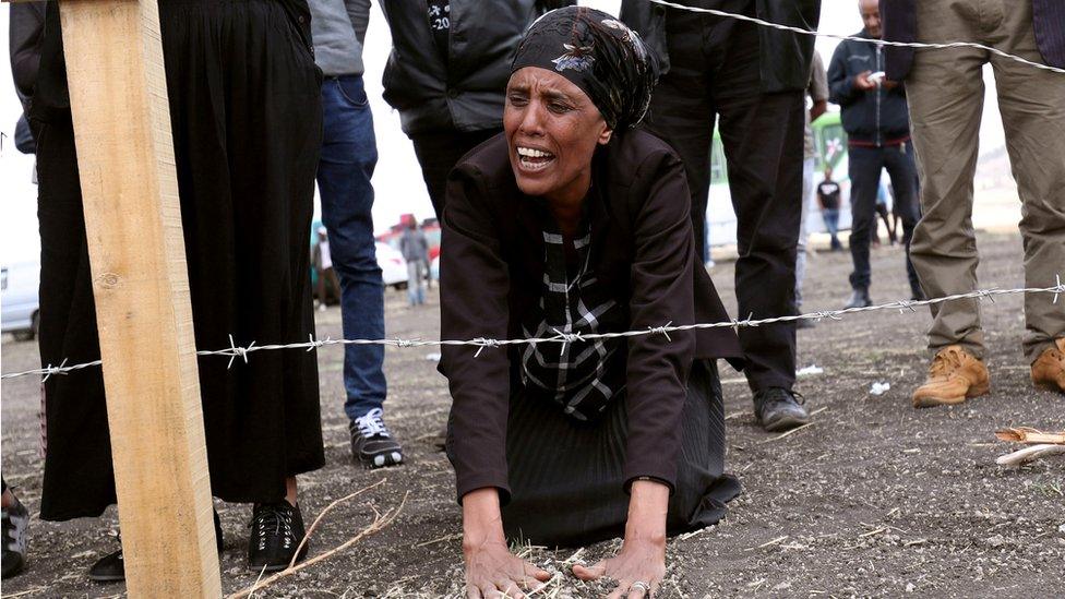 A family member of the Ethiopian Airlines crash victims mourns at the fenced-off accident site