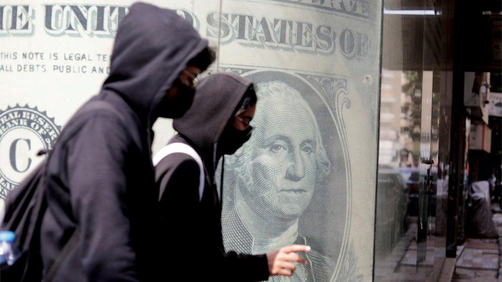 People walk past a currency exchange point in Cairo