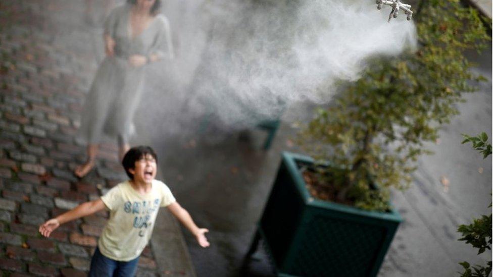 A child cools off under a water spray as a heatwave rolls over Paris, France, August 8, 2020.