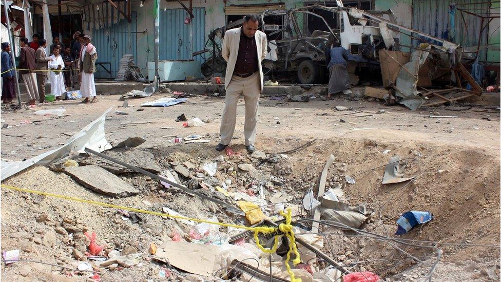 A Yemeni man stands beside the crater left by a Saudi-led coalition air strike on Dahyan, Yemen (10 August 2018)