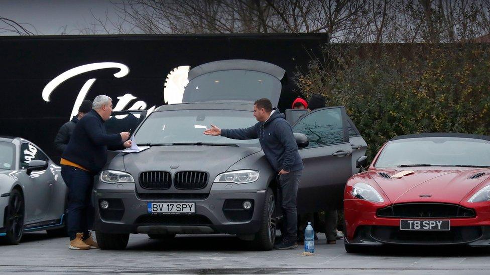 Romanian law enforcement officers complete the seizure papers for the luxury cars belonging to Andrew Tate