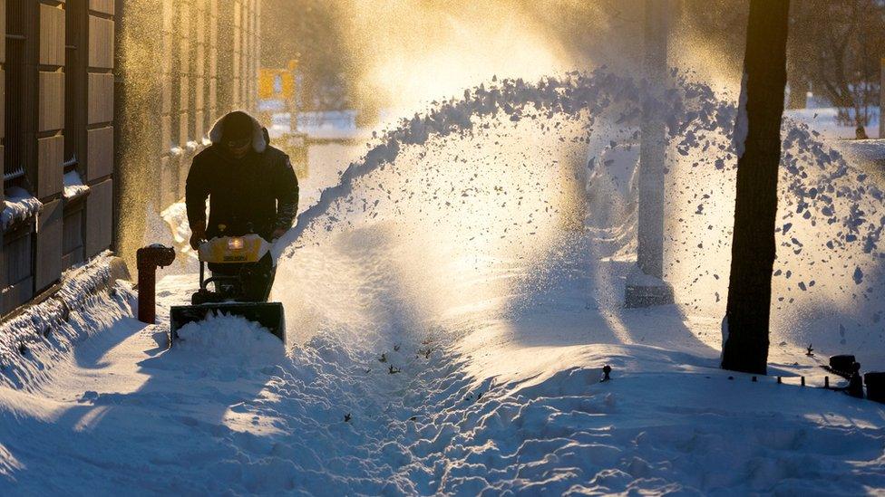 Snow is cleared along a street in the Upper West Side neighbourhood of New York Sunday, Jan. 24, 2016