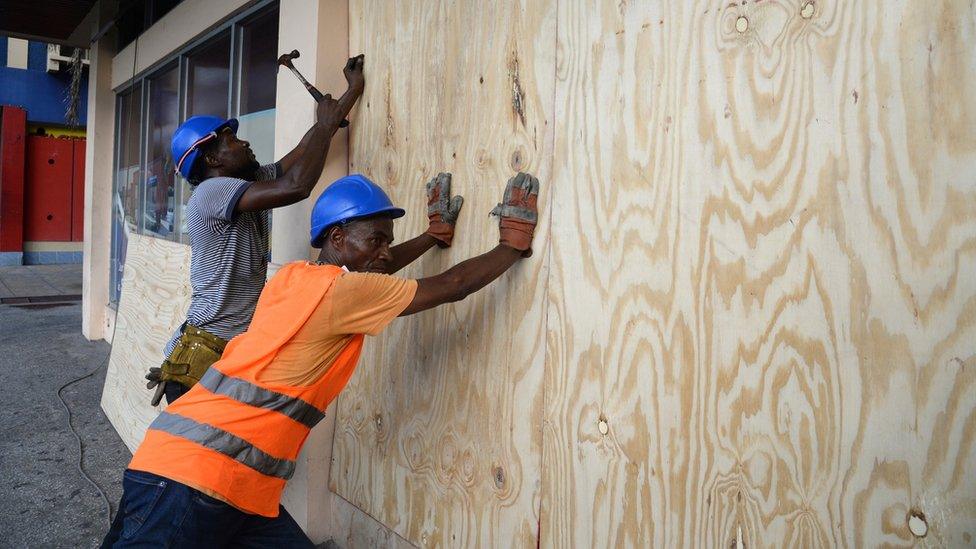 A worker nails a board to use on a storefront window as protection against hurricane Matthew in Kingston on 1 October