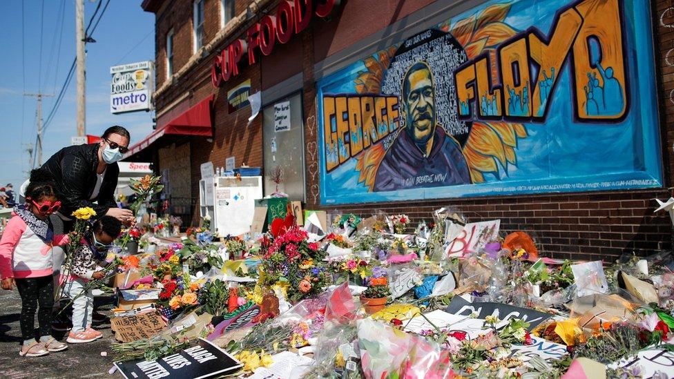 A woman and children put flowers at a makeshift memorial honoring George Floyd, at the spot where he was taken into custody, in Minneapolis, Minnesota, U.S.