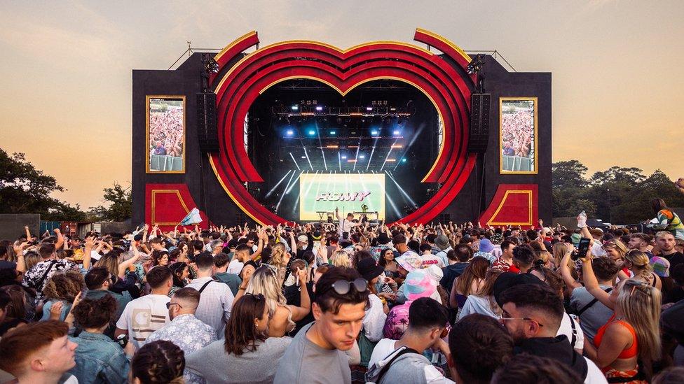 A crowd of people surrounding the main stage at dusk during Love Saves the Day festival