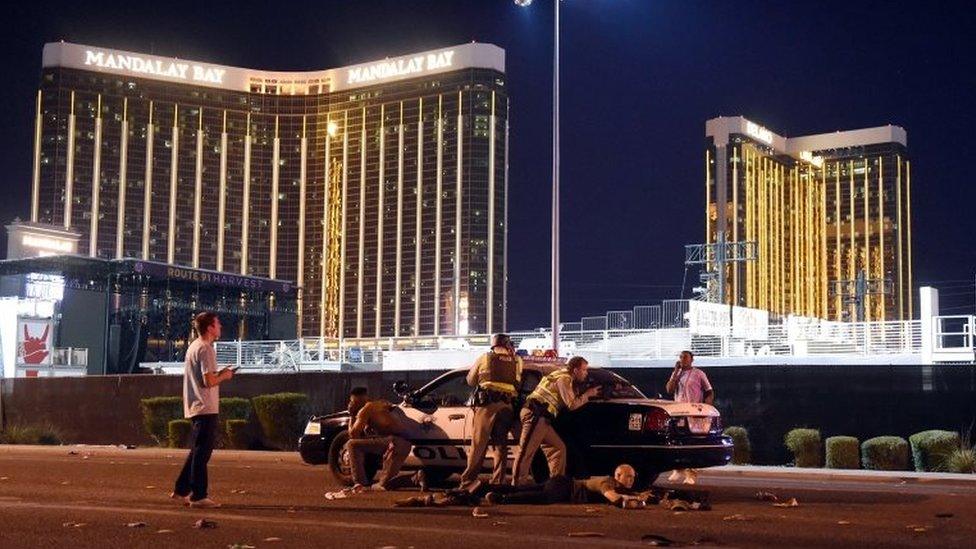 Police are seen crouching in front of vehicle outside hotel