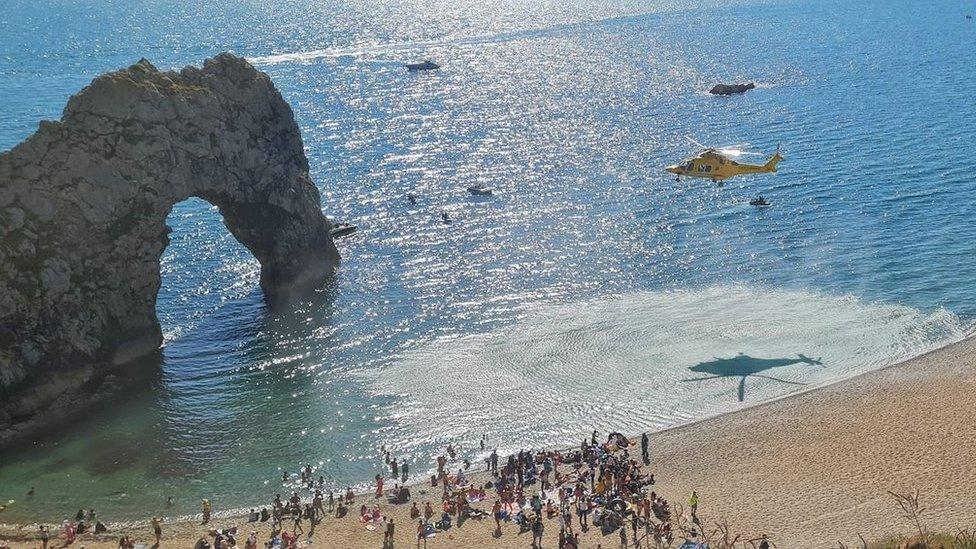 Air ambulance taking off from Durdle Door beach with Durdle Door sea arch in the background