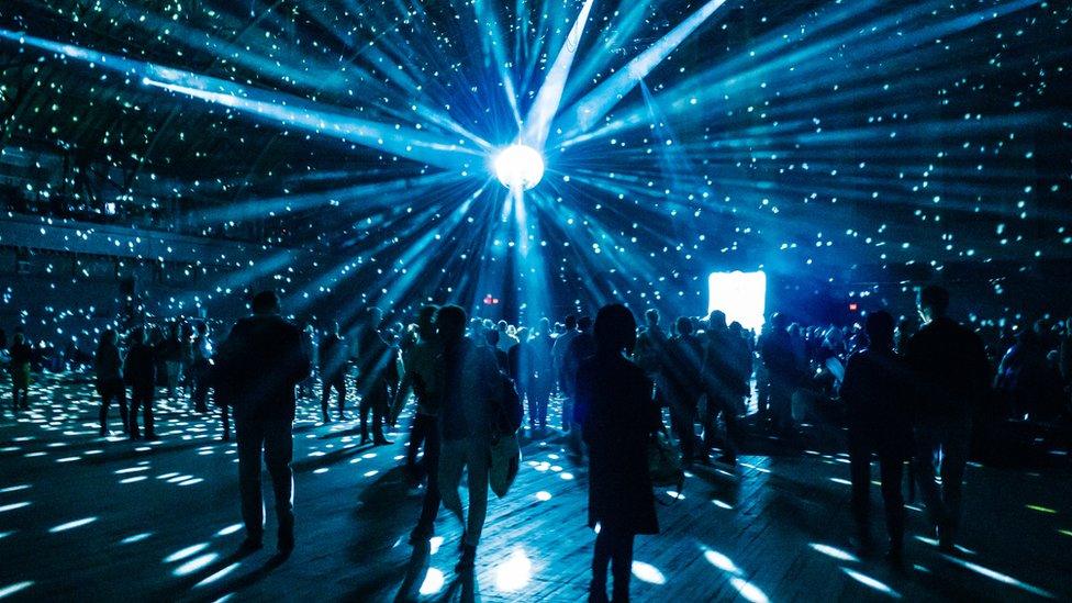 Illuminated Disco Ball Over Silhouette People In Nightclub - stock photo