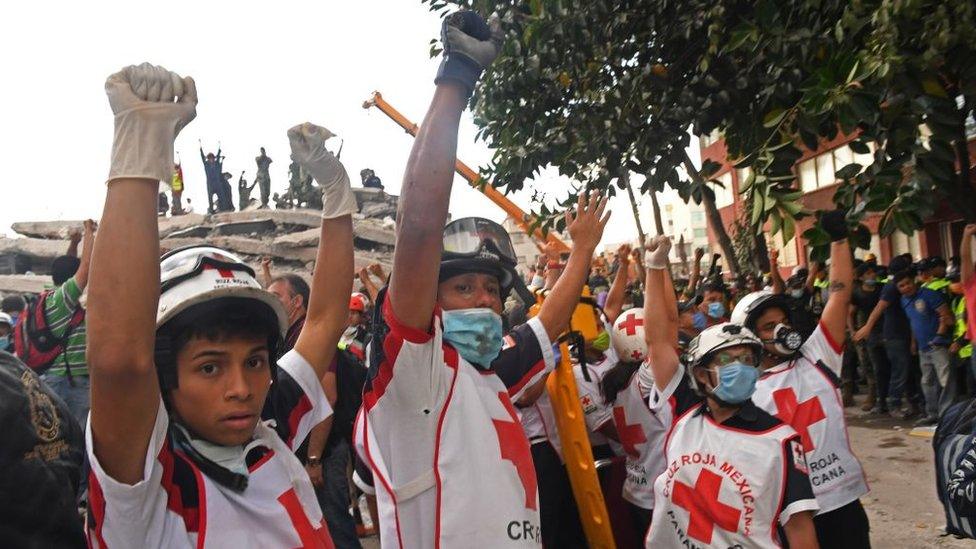 Red Cross workers hold their hands up for silence