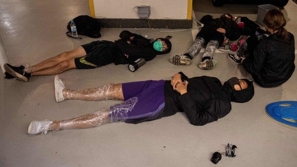 Protesters sleep on the floor of a parking lot inside the Hong Kong Polytechnic University