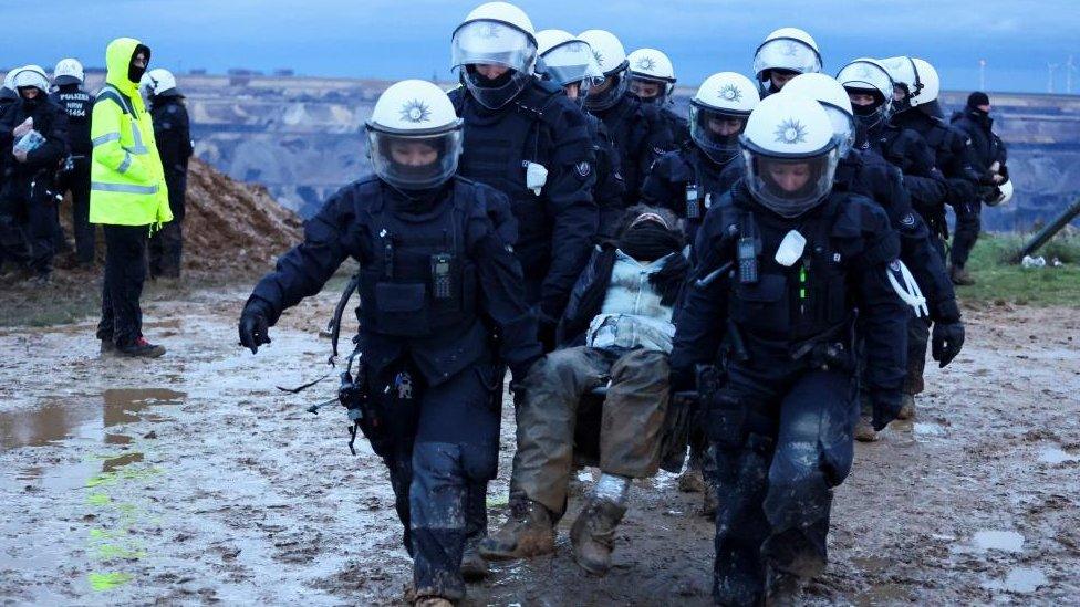 Police officers carry a demonstrator during a climate protest in Lützerath