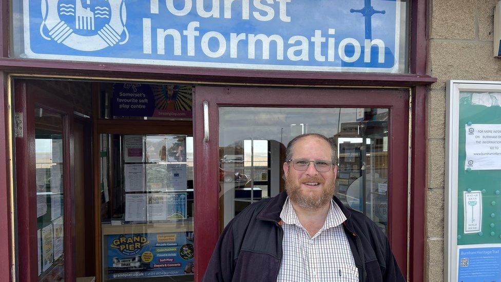 Man stood underneath Tourist Information sign