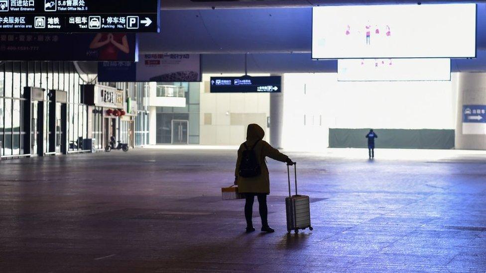 A passenger stands alone at a deserted train station