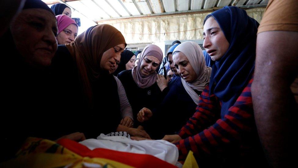 Relatives of Mohammed al-Alami mourn during his funeral near Hebron in the occupied West Bank (29 July 2021)