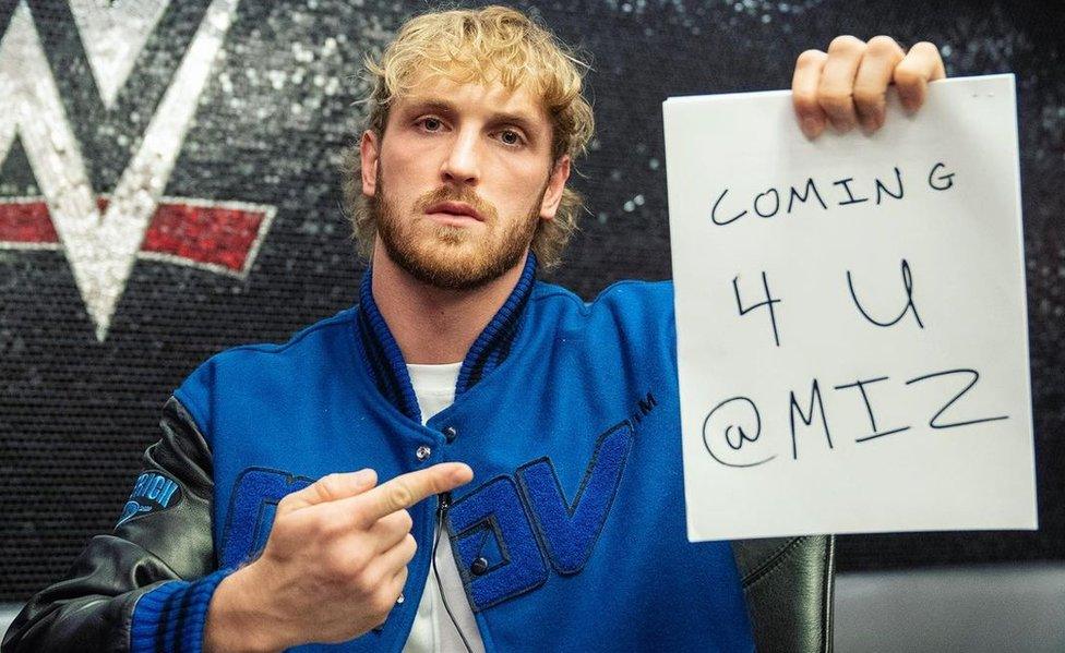 Paul holds up a handwritten sign with the message: "Comin 4 U @Miz"